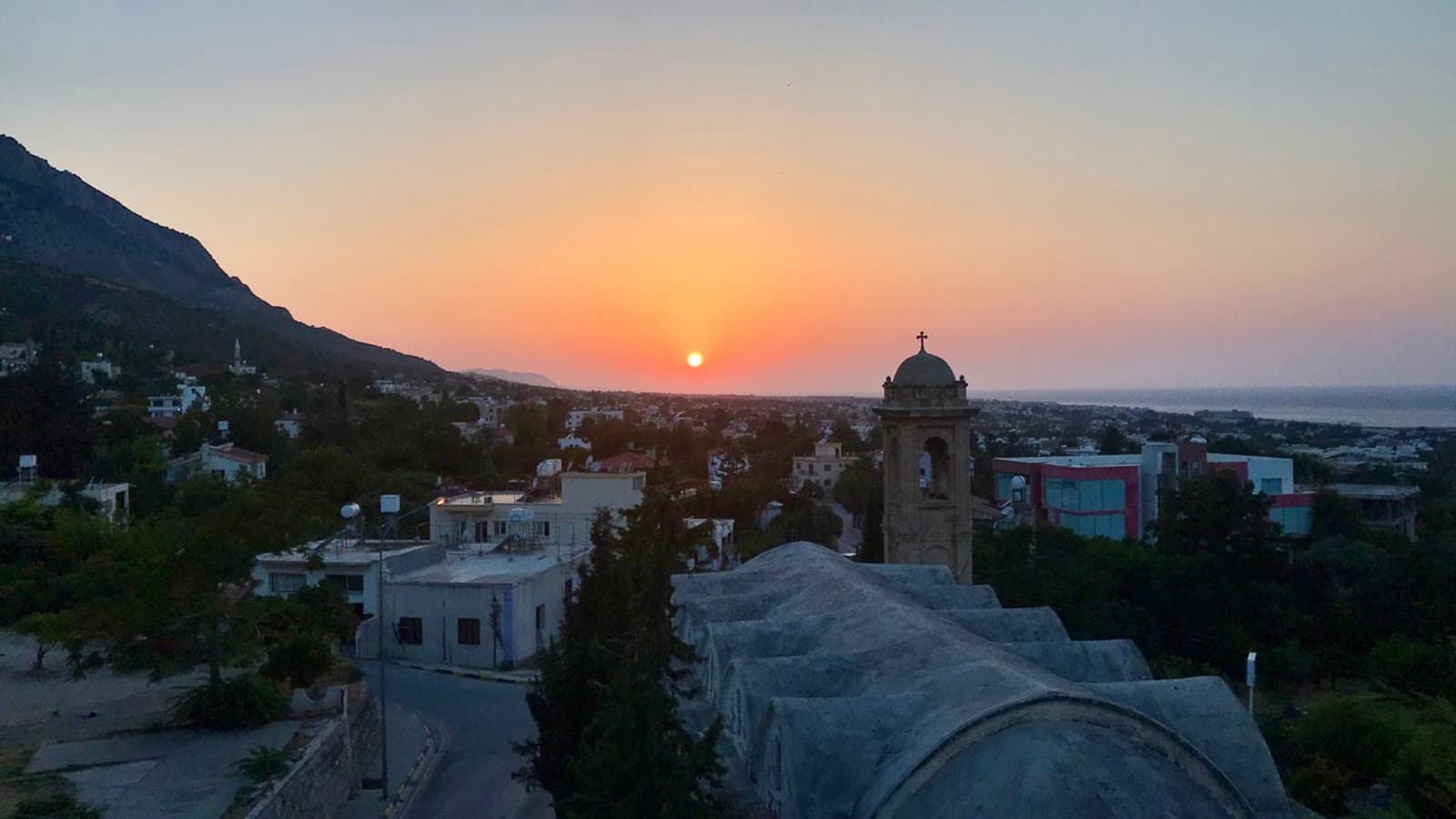 The bell tower of St Luke's church and the vaulted roofs of The Old Monastery at sunset, above Lapta and the sea.